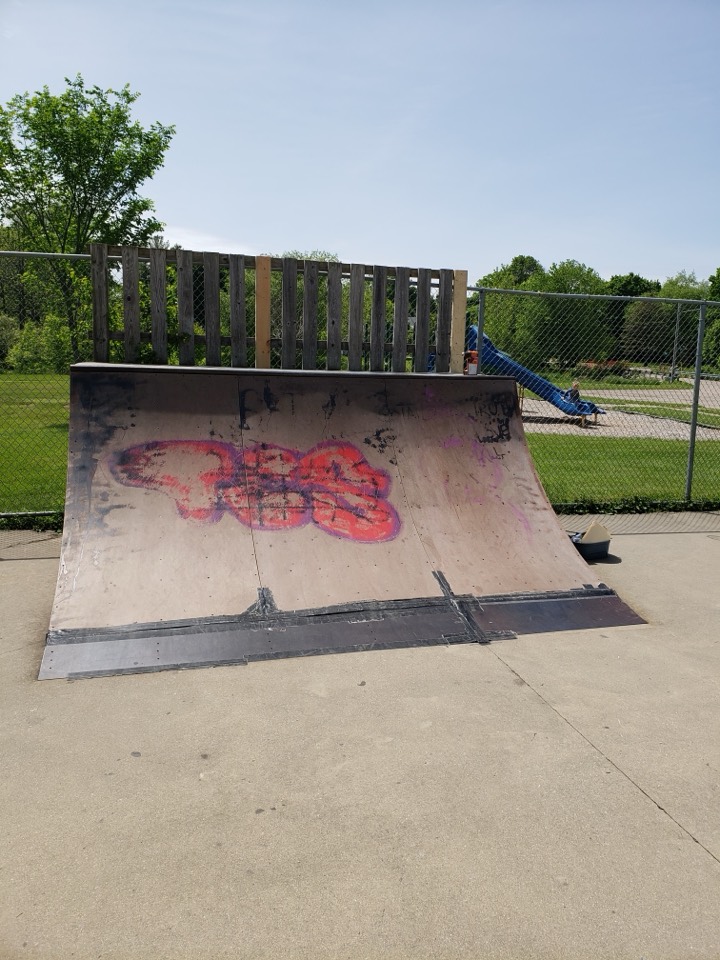 A weathered outdoor quarter pipe at Marshall Skate Park with damaged plywood
